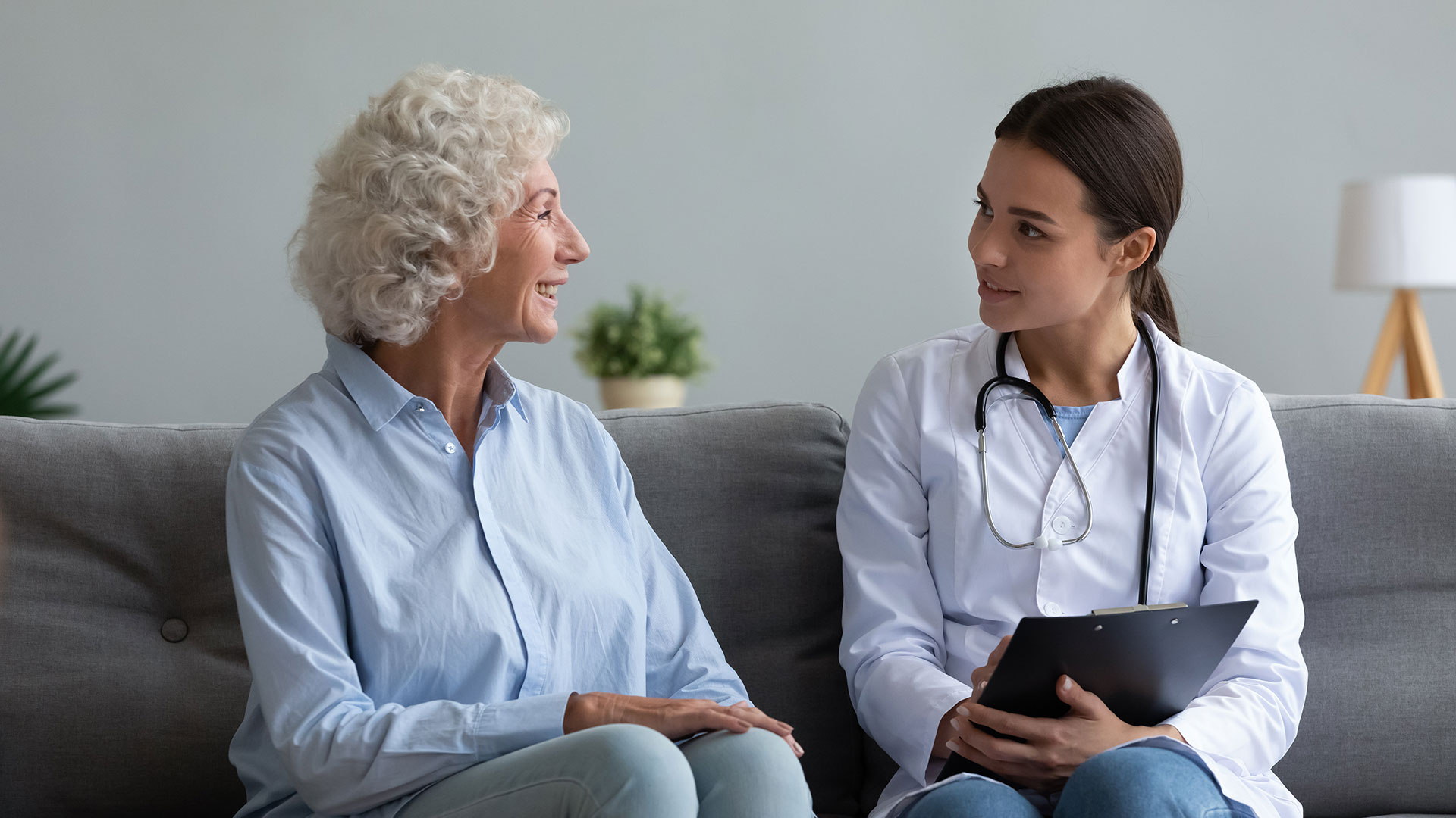 A doctor and a patient sit on a couch and talk.