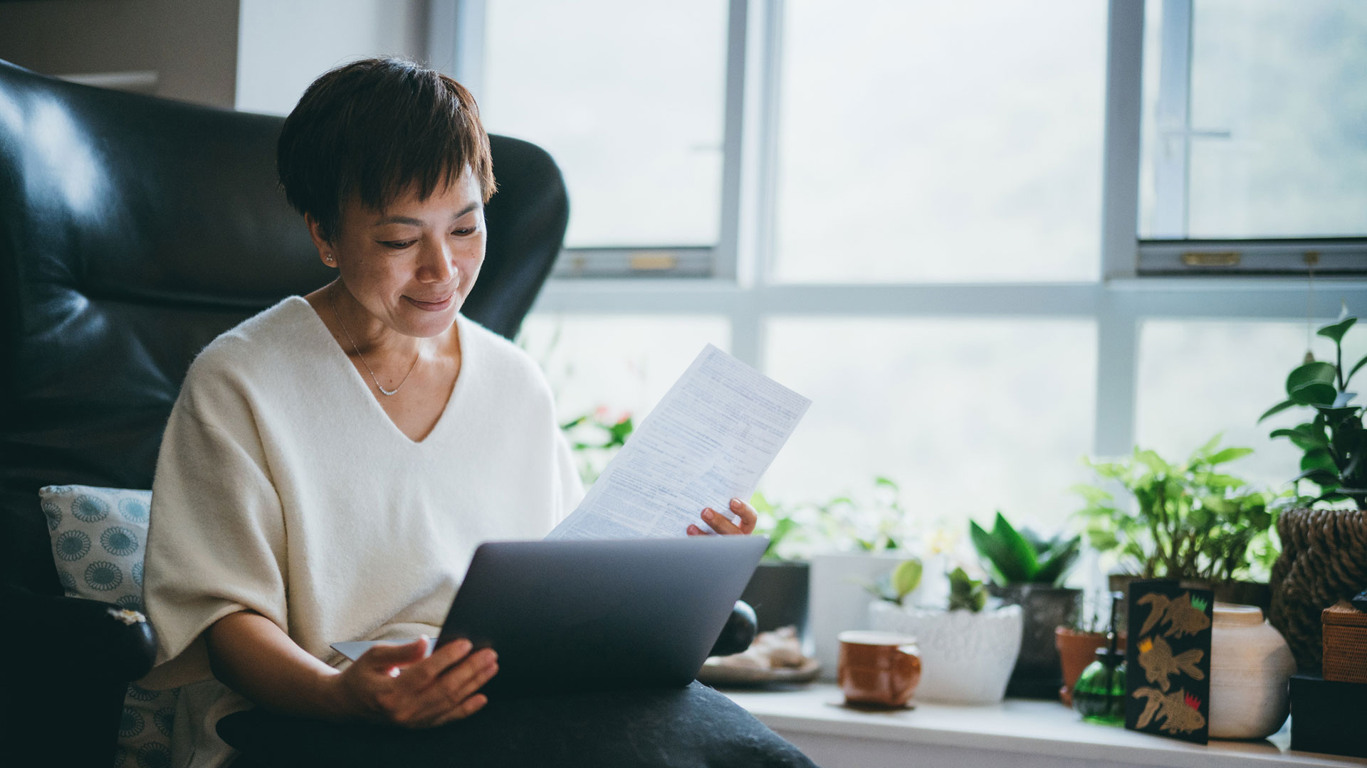 A person sits in a chair and looks at a laptop.