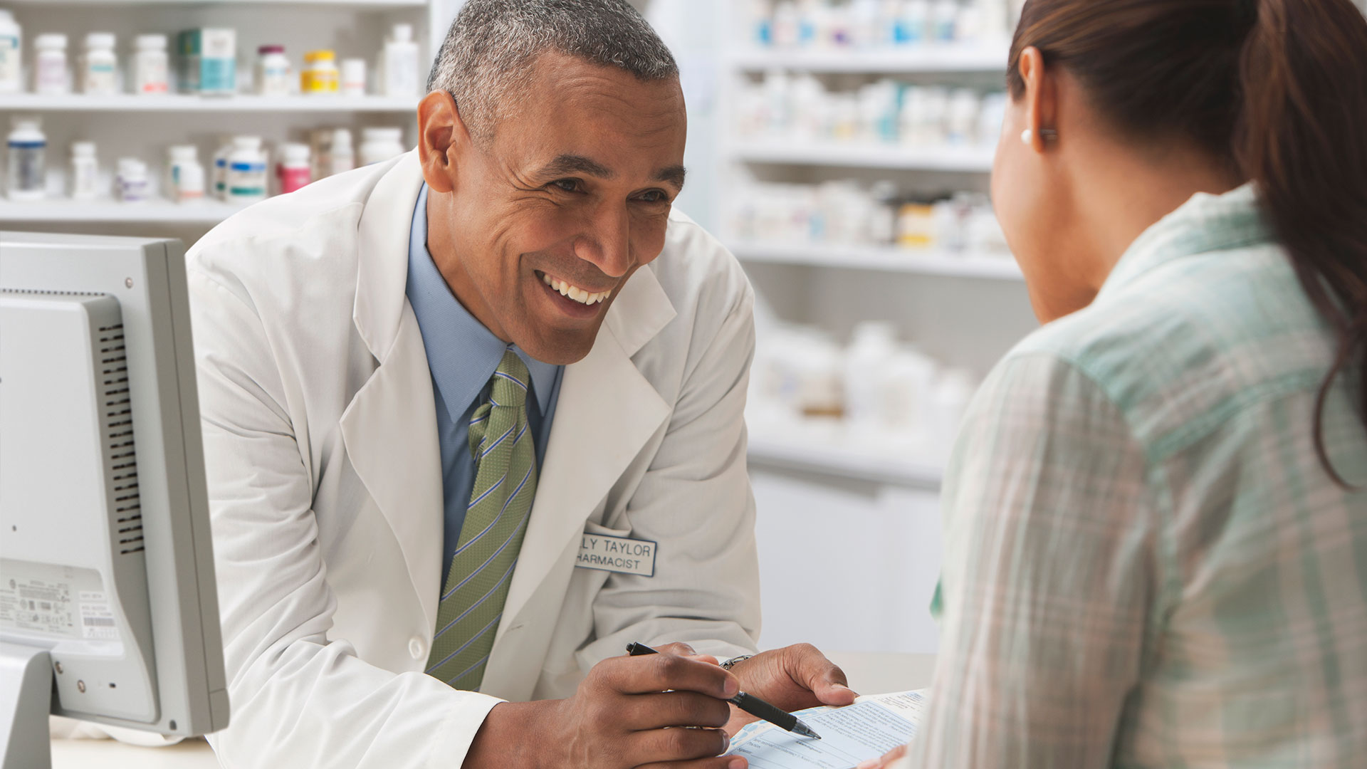 A pharmacist and a patient go over a document.