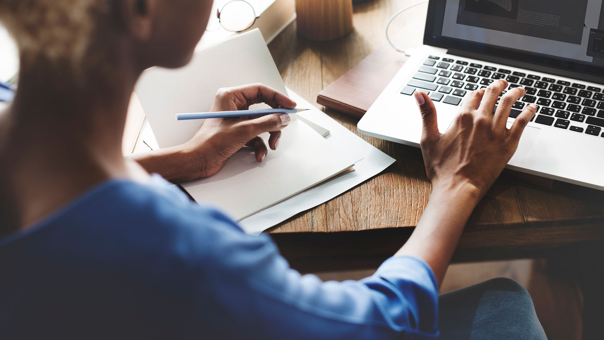 A person sits at a table and types on a laptop.