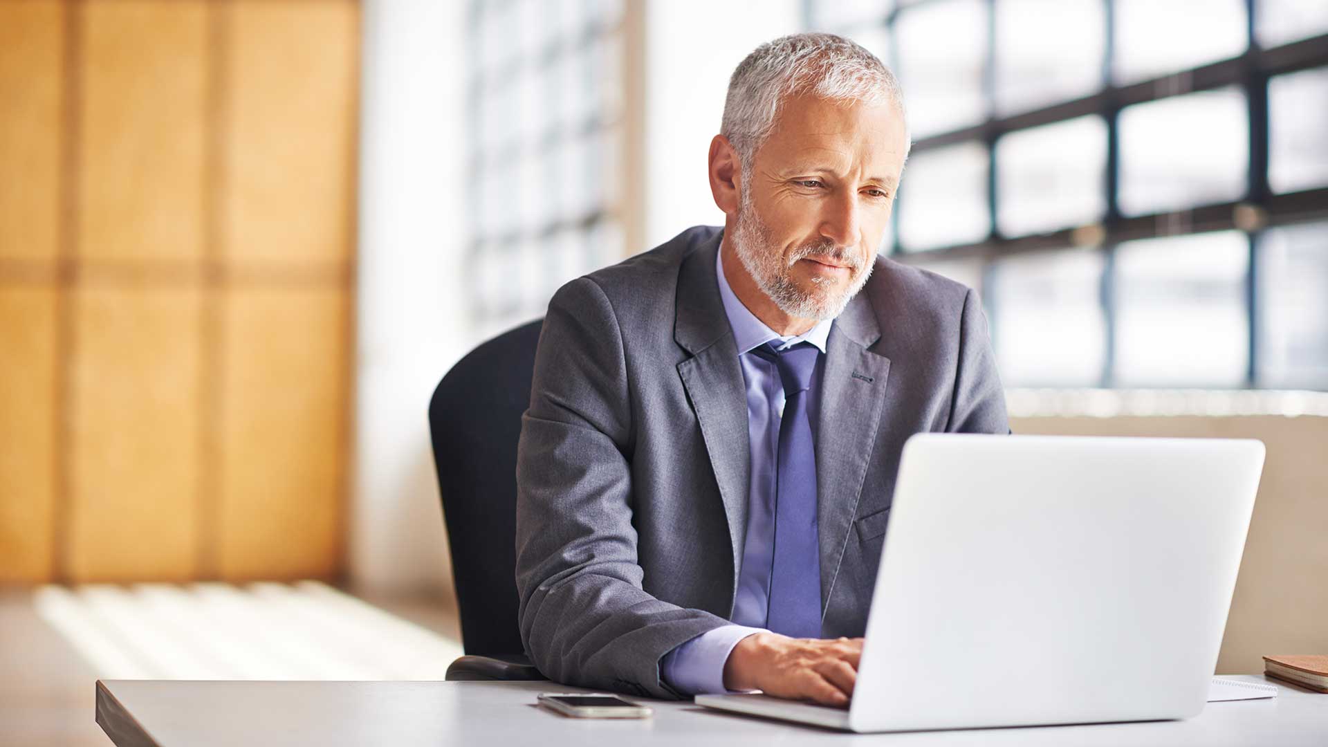 A person sits at a desk and types on a laptop.