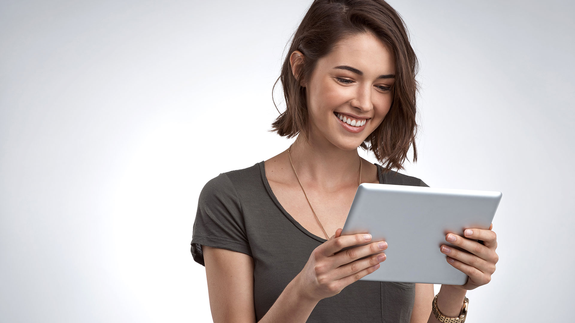 A person stands and looks at a tablet.