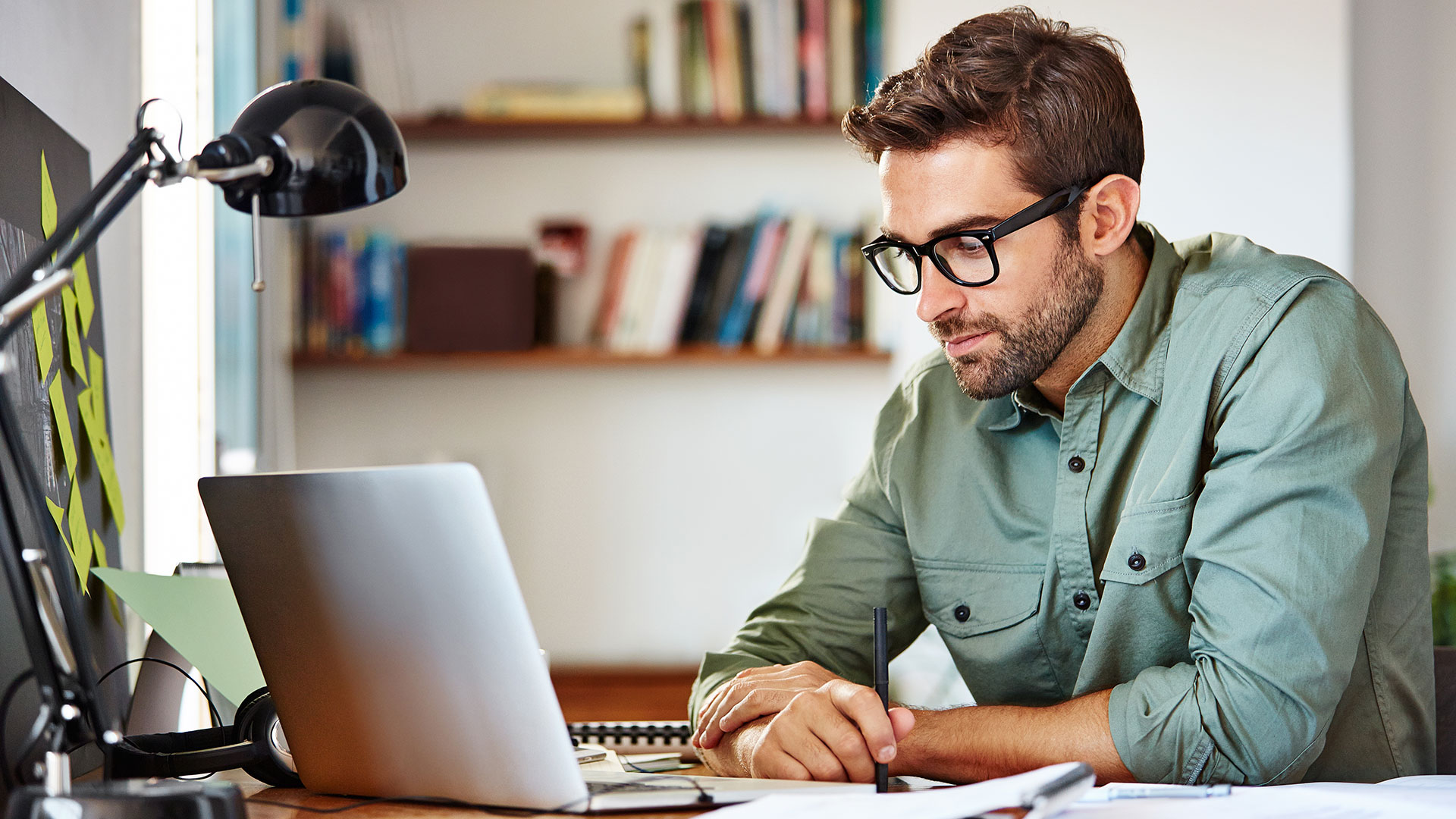 A person sits at a desk and looks at a laptop.