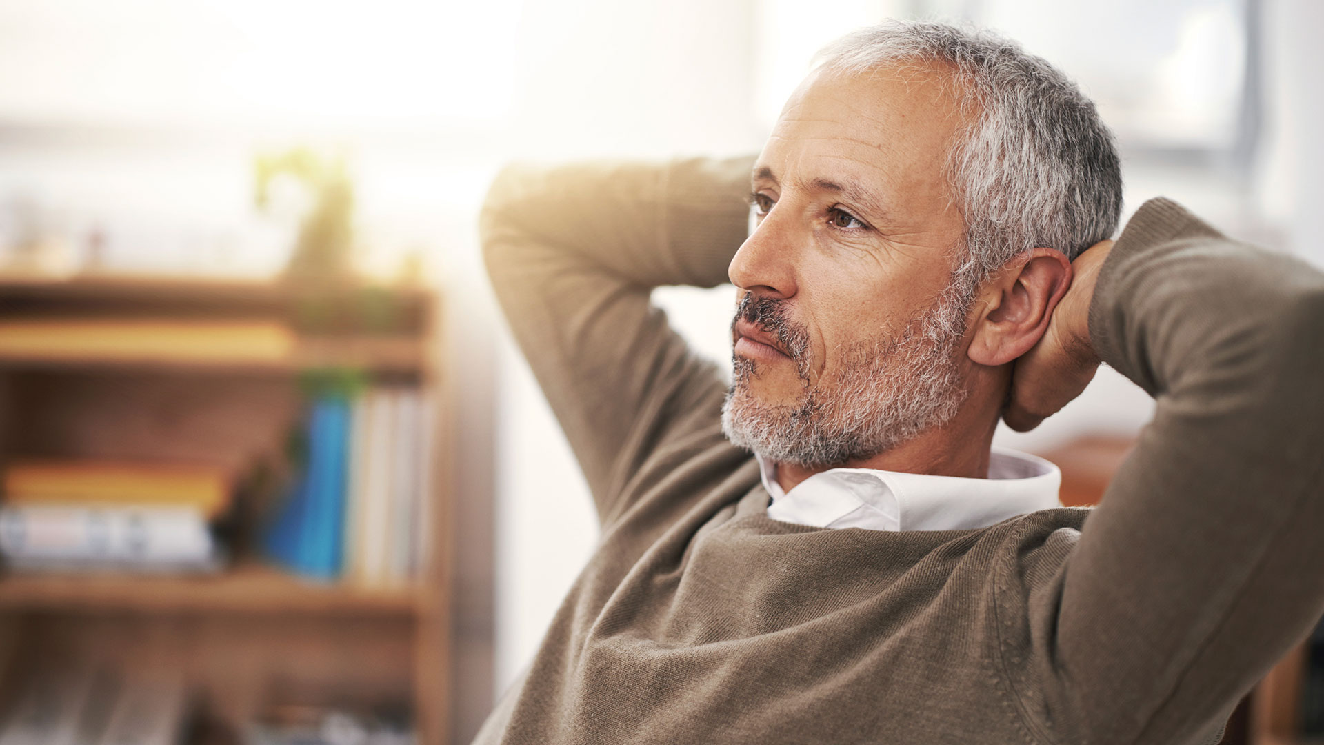 A person leans back in a chair with their arms behind their head.