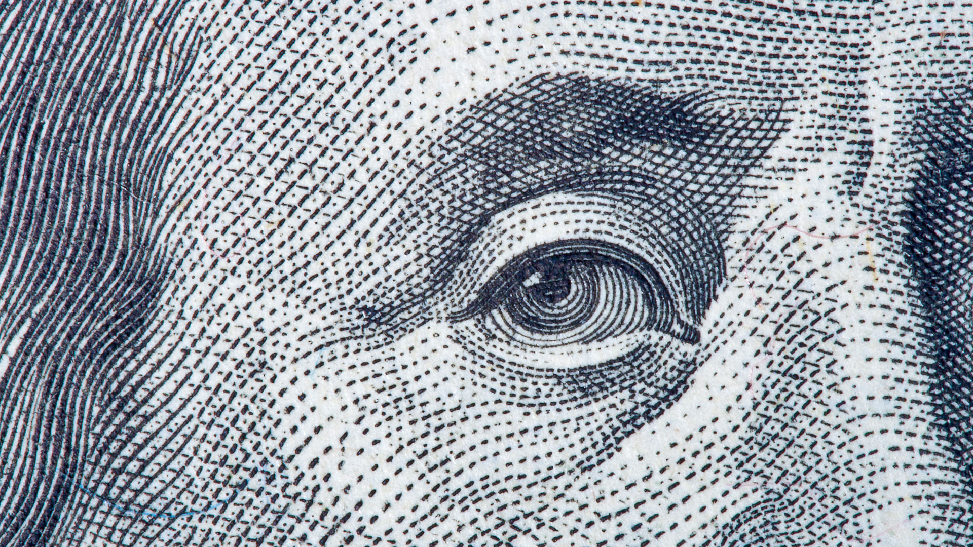 A close-up of Benjamin Franklin’s eye on a one hundred dollar bill.