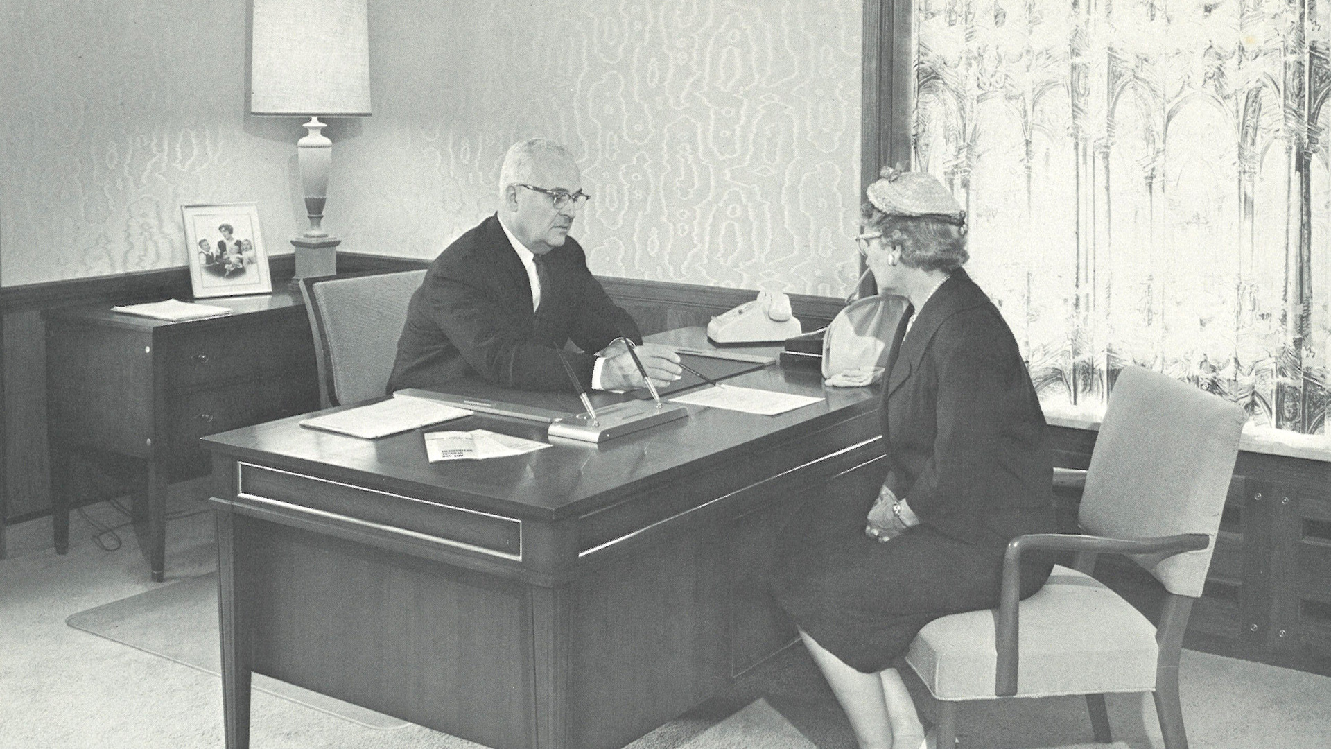 An STRS Ohio associate and an STRS Ohio member in 1962 sit at a desk and go over a document.