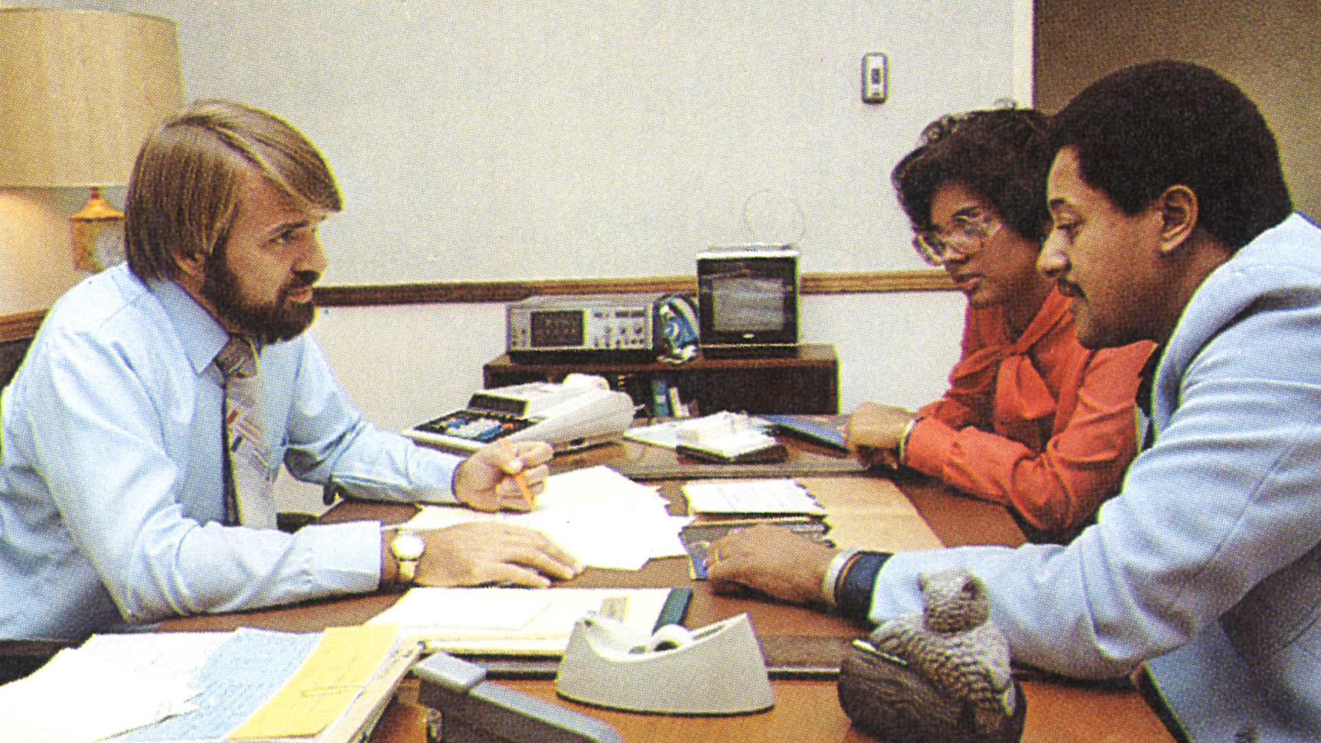 An STRS Ohio benefits counseling session during the 1970s, featuring an STRS Ohio benefits counselor and two STRS Ohio members sitting and going over documents.