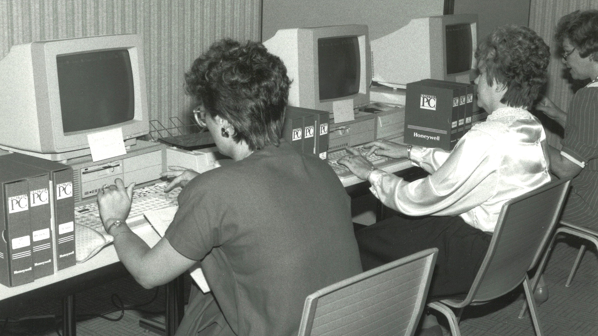 Three STRS Ohio associates in 1986 sit at a table of desktop computers and type.